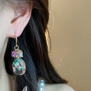 Close-up of resin flower earring with natural stones and ethnic gold hook design