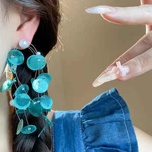 Vista detallada de pendientes de borla de concha turquesa con perlas y pernos de plata