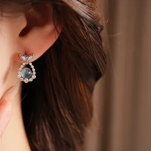 Detailed close-up of elegant silver fish tail stud earrings featuring sparkling zircons