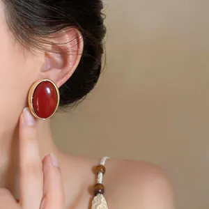 Close-up detail showing the vintage oval red resin stud earring on the model's ear