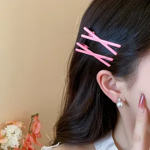 Close-up detail of vibrant pink X-shaped dopamine hair clips worn on side hair