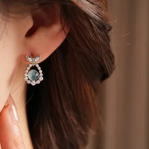 Detailed view of silver fishtail stud earrings with zircons and light blue gemstone