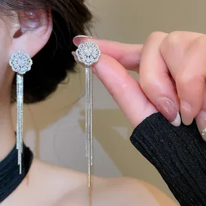 Close-up detail of geometric zircon earrings featuring long silver-tone tassels