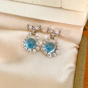 Elegant fishtail stud earrings with round blue stone and zircon accents in a gift box