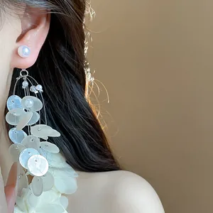 Pendientes elegantes con borlas de nácar y perlas usados por modelo, detalle de cerca