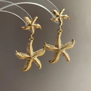 Detail showing the textured gold metal starfish pendant earrings on a display stand.