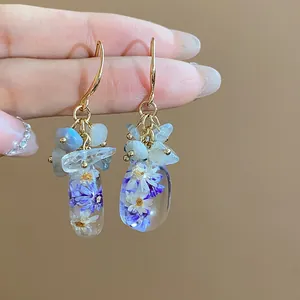 Handcrafted detail of ethnic style earrings with natural stones and resin flowers