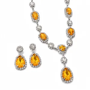 Elegant jewelry set with orange teardrop stones and crystals on a white background.