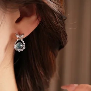 Close-up of an elegant silver fishtail earring with blue zircon and clear stones on ear