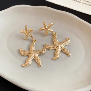 Close-up of the elegant gold wrinkled starfish pendant earrings with a textured finish.