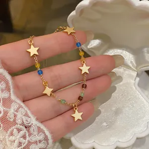 Dettaglio di bracciale con stelle dorate e perline colorate in scatola a conchiglia
