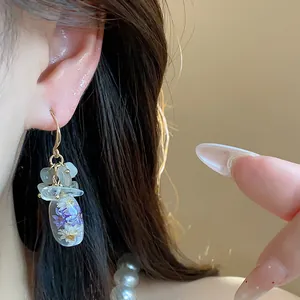 Detailed view of ethnic resin drop earrings featuring natural stones and dried flowers