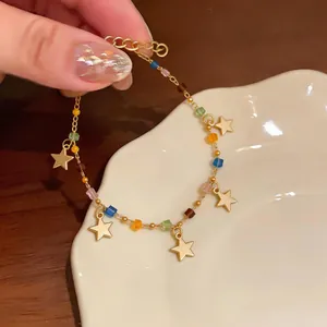 Primo piano di un bracciale in acciaio inossidabile dorato con ciondoli a stella e perline colorate