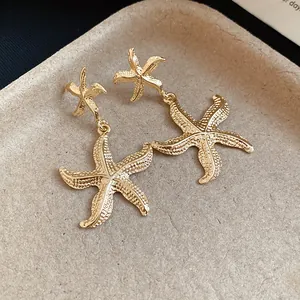 Detailed view of elegant golden starfish drop earrings featuring wrinkled metal texture