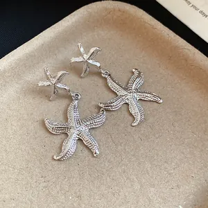 Close-up of silver metallic starfish drop earrings with a unique wrinkled texture