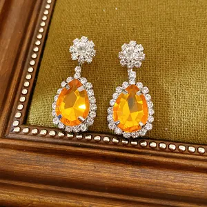Detailed view of elegant orange teardrop earrings with sparkling rhinestone halo