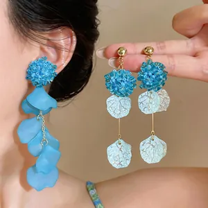 Detailed close-up of elegant blue glass flower and acrylic petal tassel earrings.