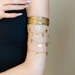 Detailansicht eines goldfarbenen Armreifs mit mehrlagigen Münzquasten und Porträtanhängern.