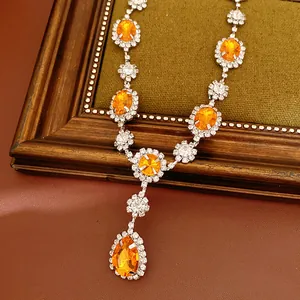 Close-up of elegant orange gemstone necklace with sparkling teardrop pendant detail.