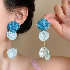 Detailed view of blue floral glass bead earrings with textured acrylic petal tassels