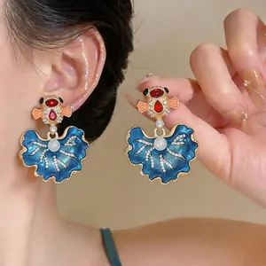 Dettaglio macro di orecchini a perla a coda di pesce stile palazzo con smalto blu e strass
