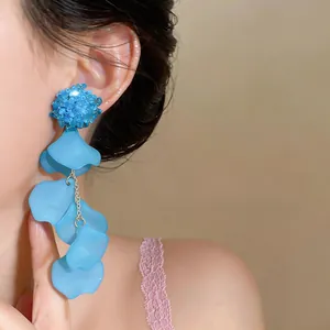 Detail of blue floral acrylic tassel earrings with translucent petals on a model's ear
