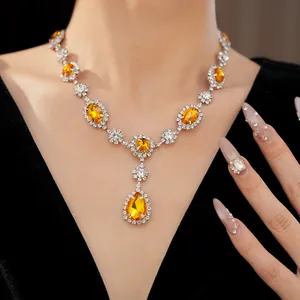 Close-up of elegant silver necklace featuring teardrop orange gems and rhinestones on model.