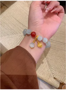 Détail d'un bracelet en perles d'oeil de chat de style vintage avec breloques au poignet