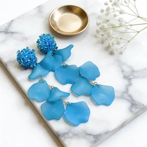 Detailed macro view of blue beaded flower studs and frosted acrylic petal dangles