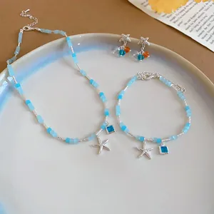Detail view of summer jewelry set with blue square beads and silver starfish charms.