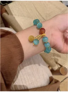 Gros plan d'un bracelet de style chinois en perles d'œil de chat sur un poignet féminin