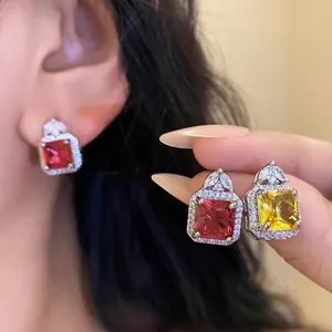 Exquisite macro shot showing square cut red and yellow zircon earrings with micro-pave halo
