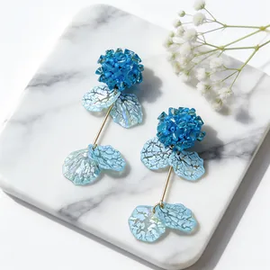 Detailed close-up of blue glass flower earrings with translucent acrylic petals