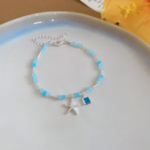 Detailed view of a summer style starfish beaded bracelet with blue square charm.