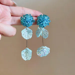 Detailed view of handmade blue glass flower earrings with acrylic petal tassels