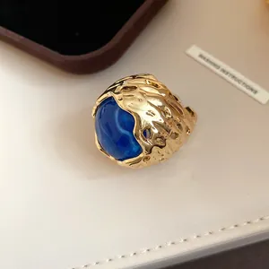 Gedetailleerd beeld van vintage gouden ring met grote ronde blauwe harssteen