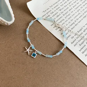 Detailed view of a light blue bead bracelet featuring starfish and square crystal charms