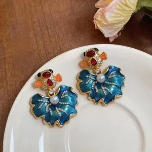 Primo piano di orecchini vintage in smalto blu con perle e pietre rosse in stile barocco