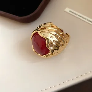 Detailweergave van een vintage goudkleurige ring met textuur en een grote rode harssteen