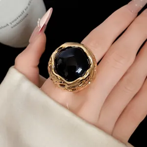 Detail van een vintage ronde ring van zwarte hars met een gehamerde goudkleurige rand