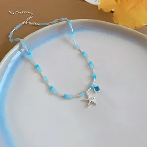 Close-up detail of a summer starfish pendant necklace featuring blue beads and silver charms