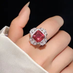 Close-up detail of an elegant square red zircon open ring with halo accents on a finger