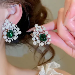 Elegant luxury stud earrings featuring green resin stone surrounded by small white pearls