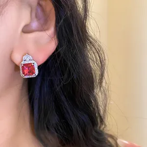 Close-up of red square zircon earring with halo stones on ear