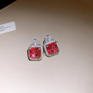 Close-up detail of exquisite square red zircon stud earrings with sparkling halo