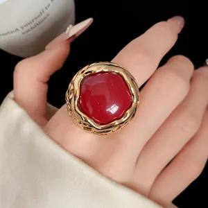 Detailopname van een ronde rode harsring in vintage stijl met een goudkleurige band