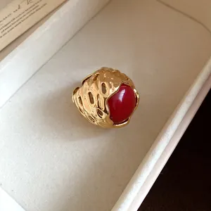 Macro-detail van een vintage gouden opengewerkte ring met een grote rode harskraal erin