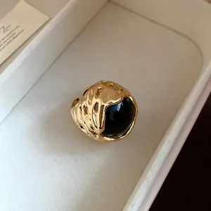 Detailopname van een vintage gouden ring met een grote zwarte harsbol in het midden