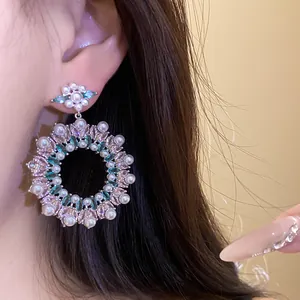 Close-up of model wearing large circular pearl and marquise cubic zirconia earrings