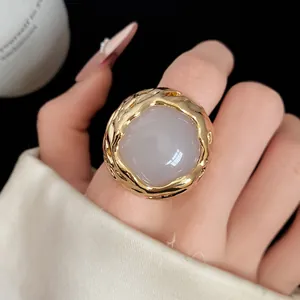 Gedetailleerd overzicht van een vintage ronde harsring met een getextureerd goud frame op vinger